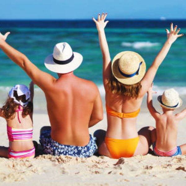 happy family father, mother and children backs on the beach at sea